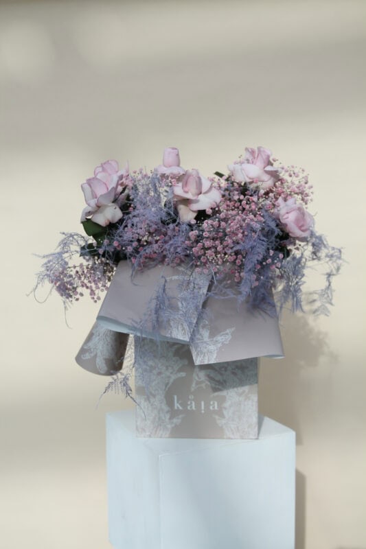 Elegant pink and purple flower bouquet featuring roses and baby's breath arranged in a white gift box, perfect for special occasions or home decor.