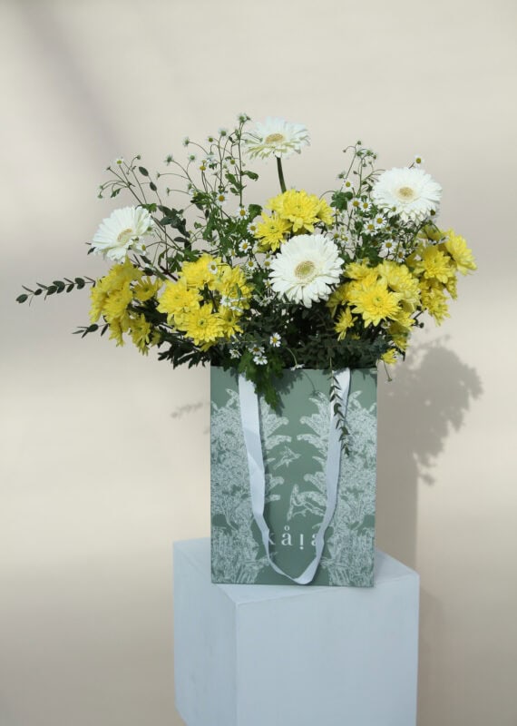 Elegant bouquet of white and yellow flowers arranged in a gift bag, perfect for special occasions or home decor.
