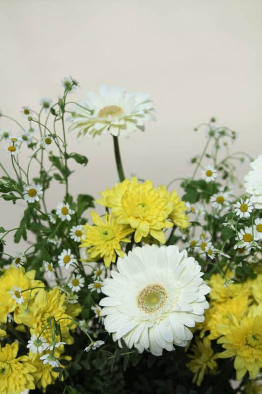 Fresh yellow and white flowers including daisies and chrysanthemums arranged beautifully for decoration or gifting. Perfect for spring and summer floral displays.
