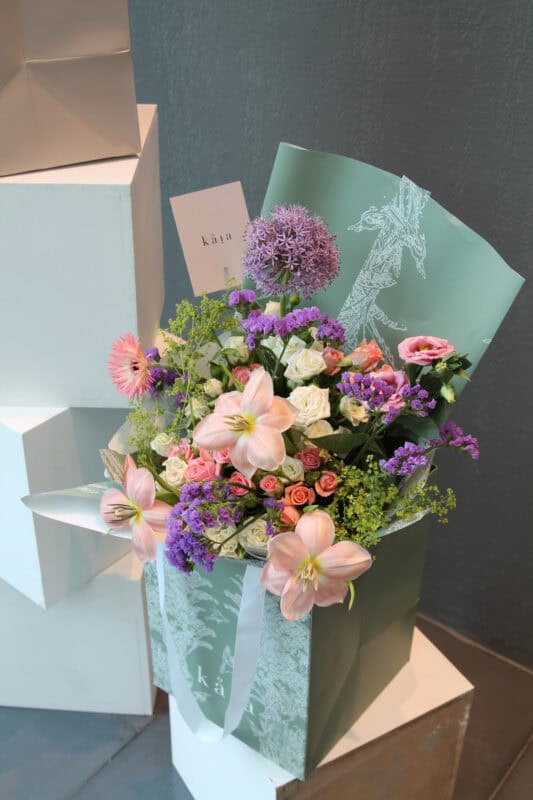 Elegant floral arrangement with pink lilies, purple alliums, and roses.