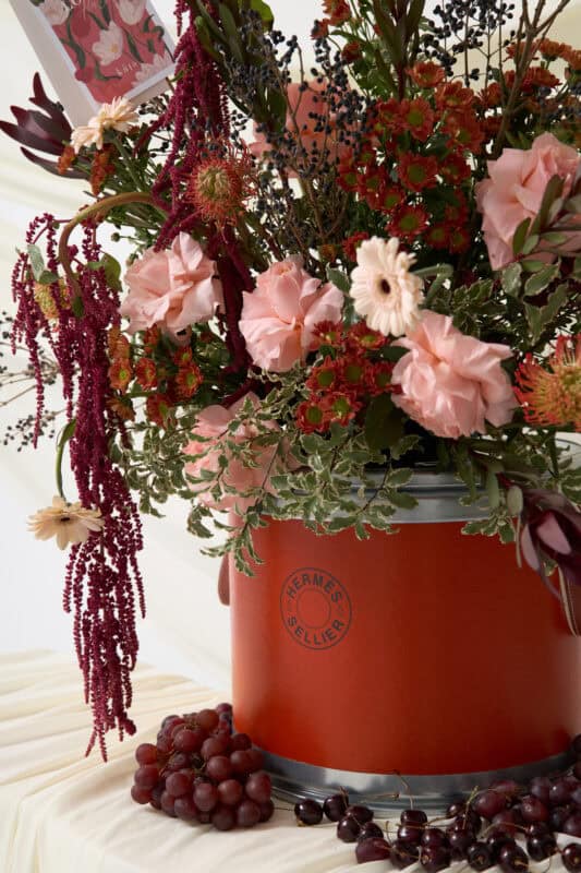 Elegant floral bouquet featuring pink roses, white daisies, and deep red accents in a stylish orange vase. Perfect for weddings, events, or home decor.