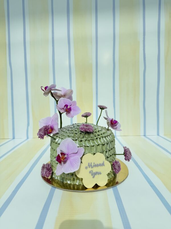 Elegant orchid-themed cake with pink orchids and green leaves, perfect for special occasions.