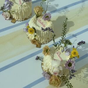 Vegan cakes decorated with fresh flowers for a celebration, featuring white icing, floral accents, and elegant design, ideal for special occasions and events.