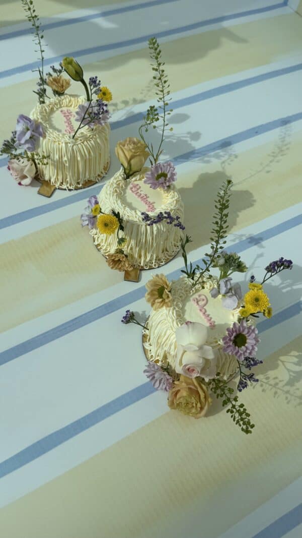 Vegan cakes decorated with fresh flowers for a celebration, featuring white icing, floral accents, and elegant design, ideal for special occasions and events.
