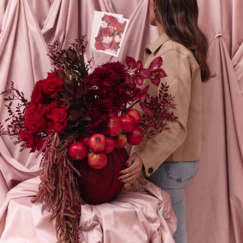 Elegant floral arrangement featuring deep red roses, dahlias, and apples for Garnet No. 9.