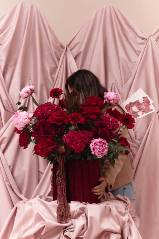 Beautiful floral bouquet featuring red and pink flowers, set against soft pink draped fabric, perfect for romantic occasions and floral decor.