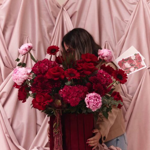 Beautiful floral bouquet featuring red and pink flowers, set against soft pink draped fabric, perfect for romantic occasions and floral decor.
