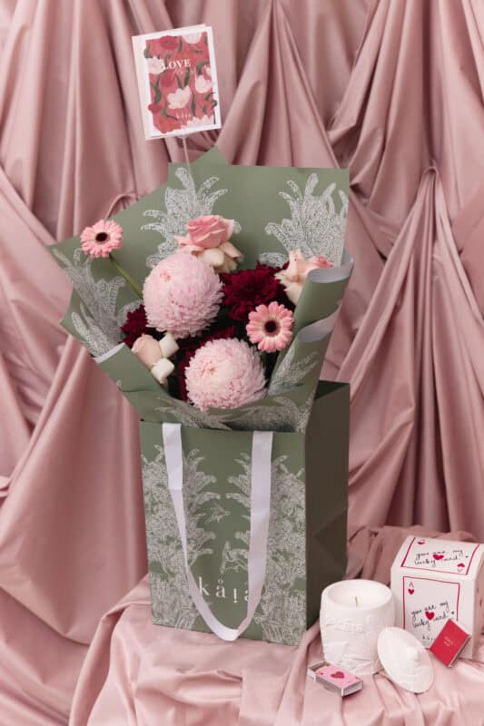 Elegant floral arrangement with pink and burgundy blooms, including roses and chrysanthemums, wrapped in stylish green and white paper, perfect for expressing love and affection.