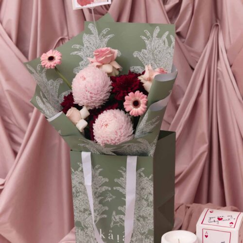 Elegant floral arrangement with pink and burgundy blooms, including roses and chrysanthemums, wrapped in stylish green and white paper, perfect for expressing love and affection.