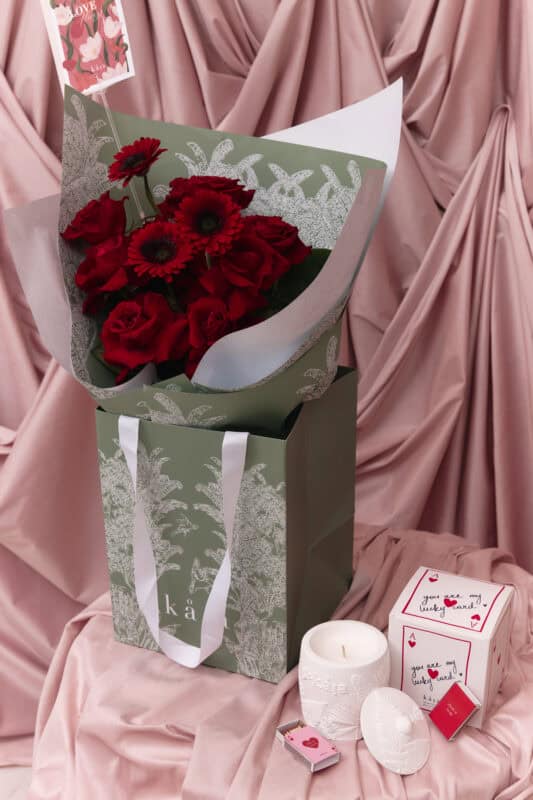 Elegant red flower bouquet with roses and gerbera daisies in a decorative box.