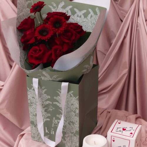 Elegant red flower bouquet with roses and gerbera daisies in a decorative box.