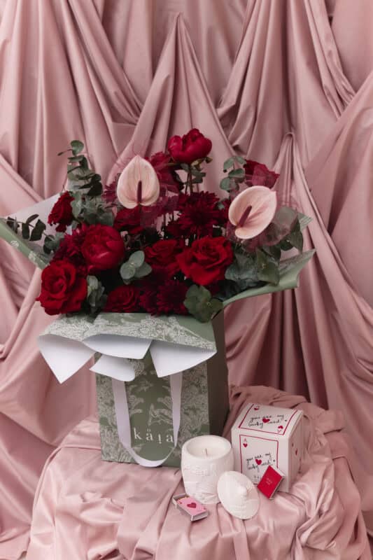 Elegant floral arrangement with roses and calla lilies in a decorative box.