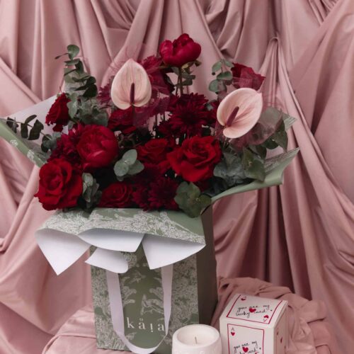 Elegant floral arrangement with roses and calla lilies in a decorative box.