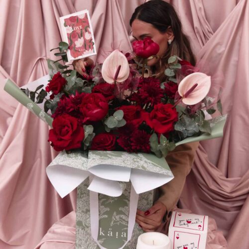 Beautiful floral arrangement with red roses, pink anthuriums, and greenery, perfect for celebrating love and special moments.
