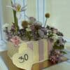 Elegant floral cake decorated with pink roses, white lilies, and assorted fresh flowers for special occasions.