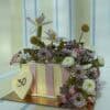 Beautiful floral cake decorated with fresh flowers including orchids, daisies, and roses in pastel shades, perfect for celebrations and special occasions.