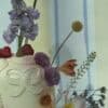 A beautiful floral arrangement featuring a variety of colorful flowers including pink, purple, yellow, and white blooms in a decorative vase. Perfect for weddings, events, or home decor.