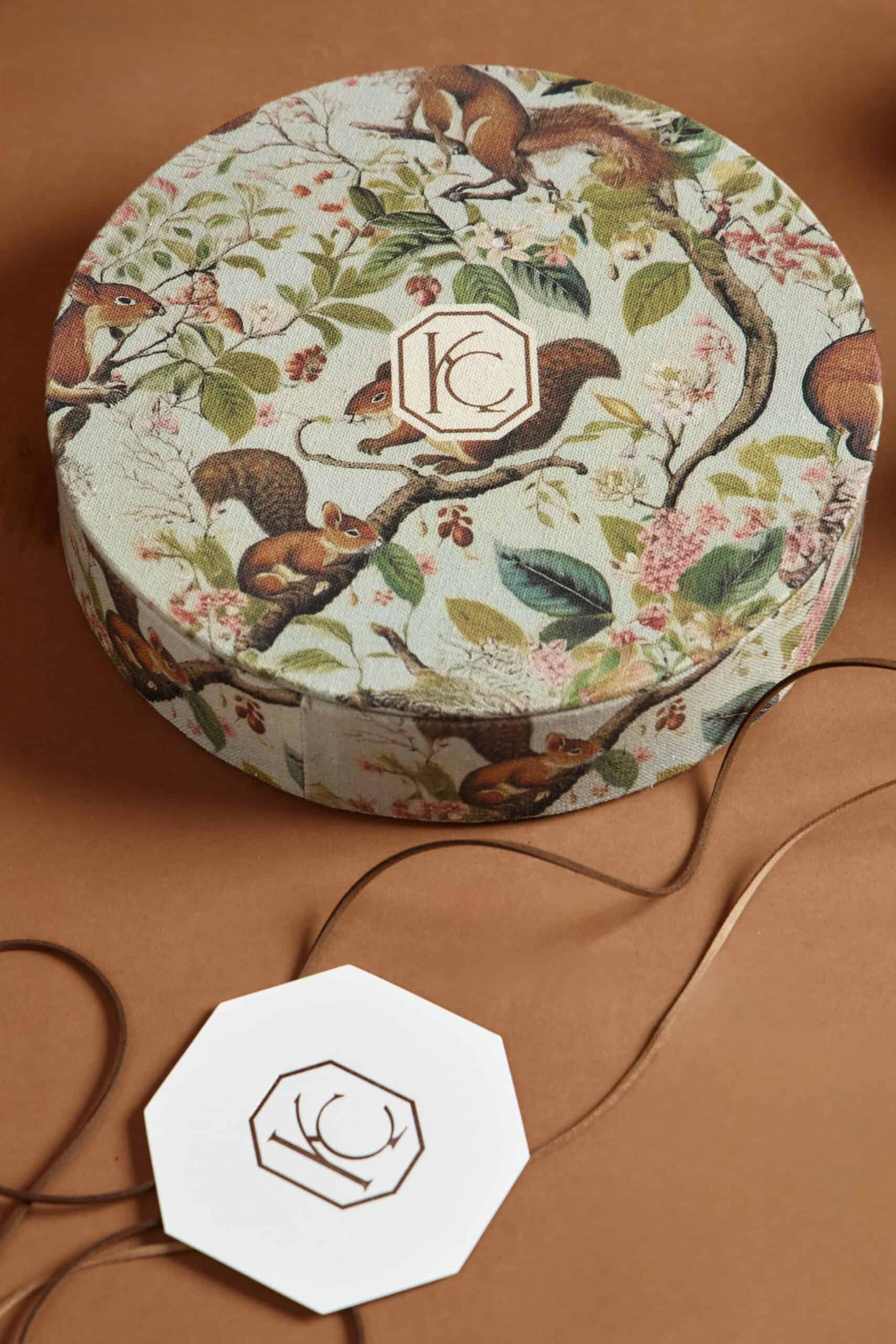 Decorative round gift box featuring a detailed squirrel and nature scene, perfect for elegant gift presentation.